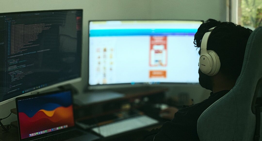 Software developer writing code on multiple monitors in a dark office